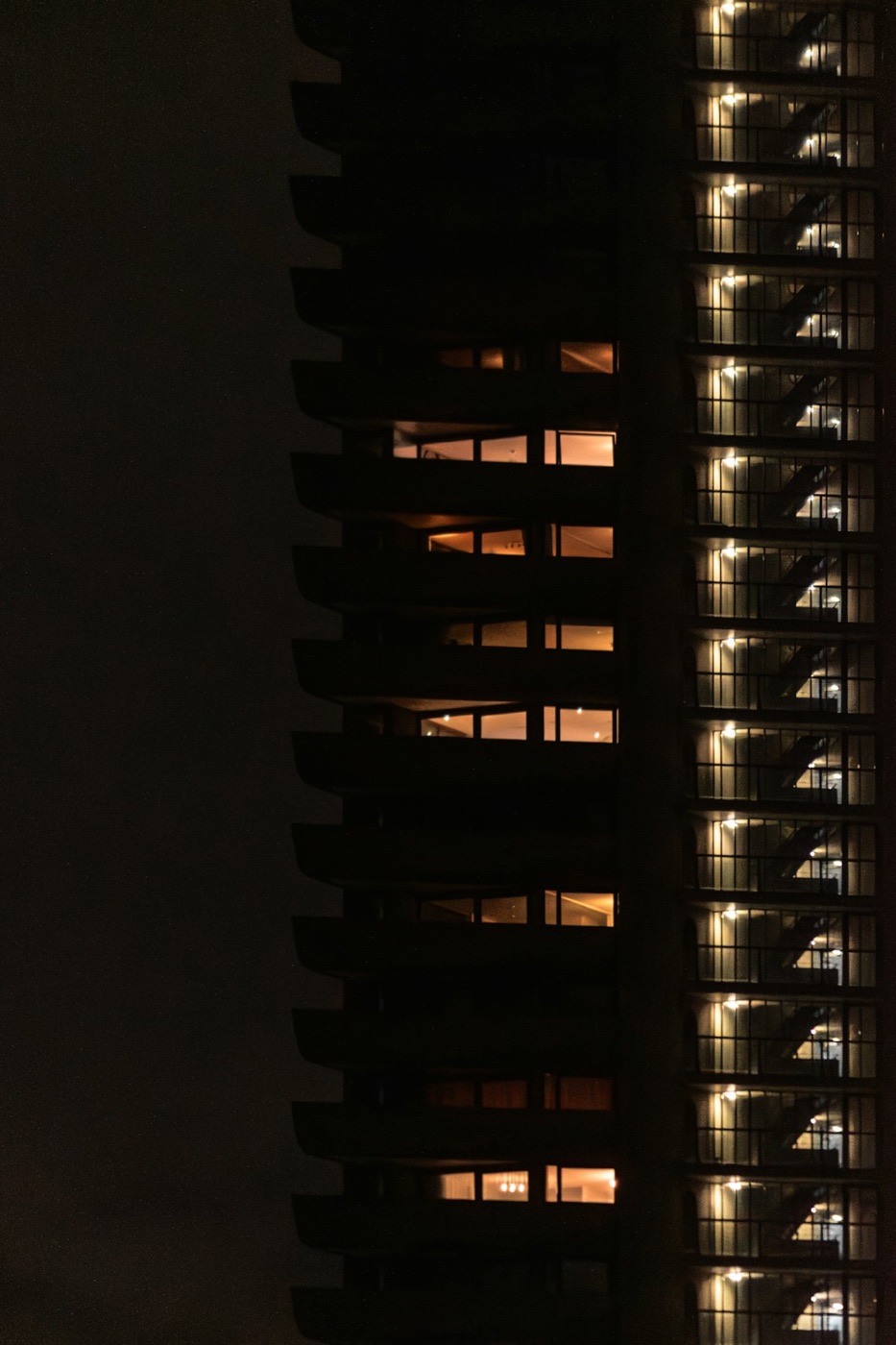 Ventanas encendidas en la fachada de una torre residencial de noche