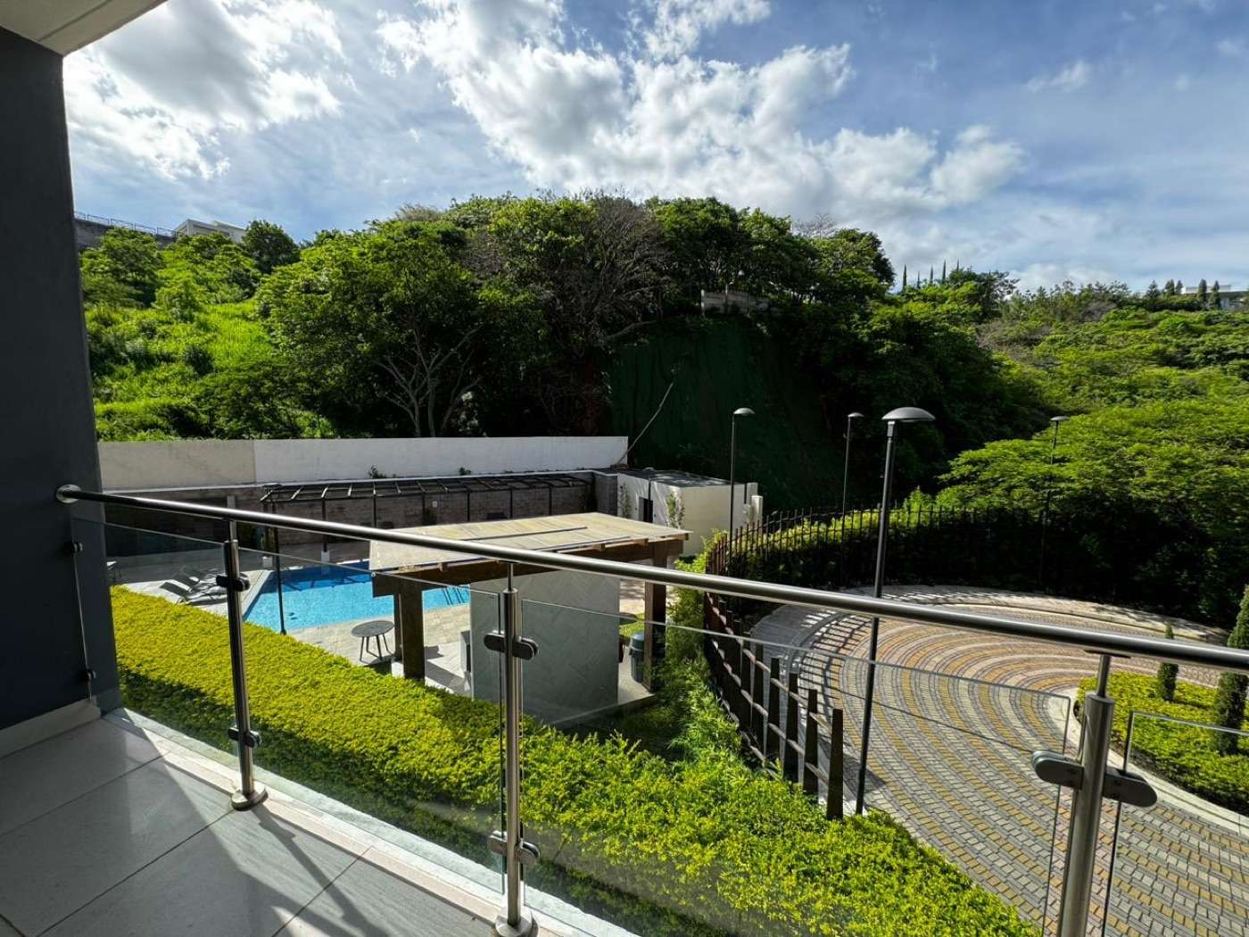 Las áreas verdes del conjunto vistas desde un balcón, con la piscina abajo